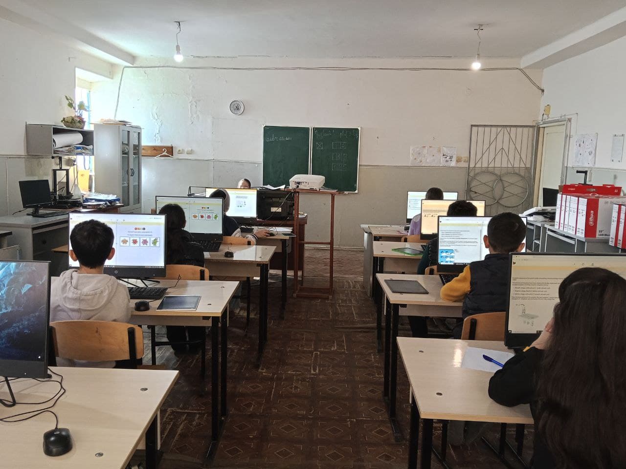 A full computer room in Ijevan, every screen showing a Bebras task, bebras.am written on the board.