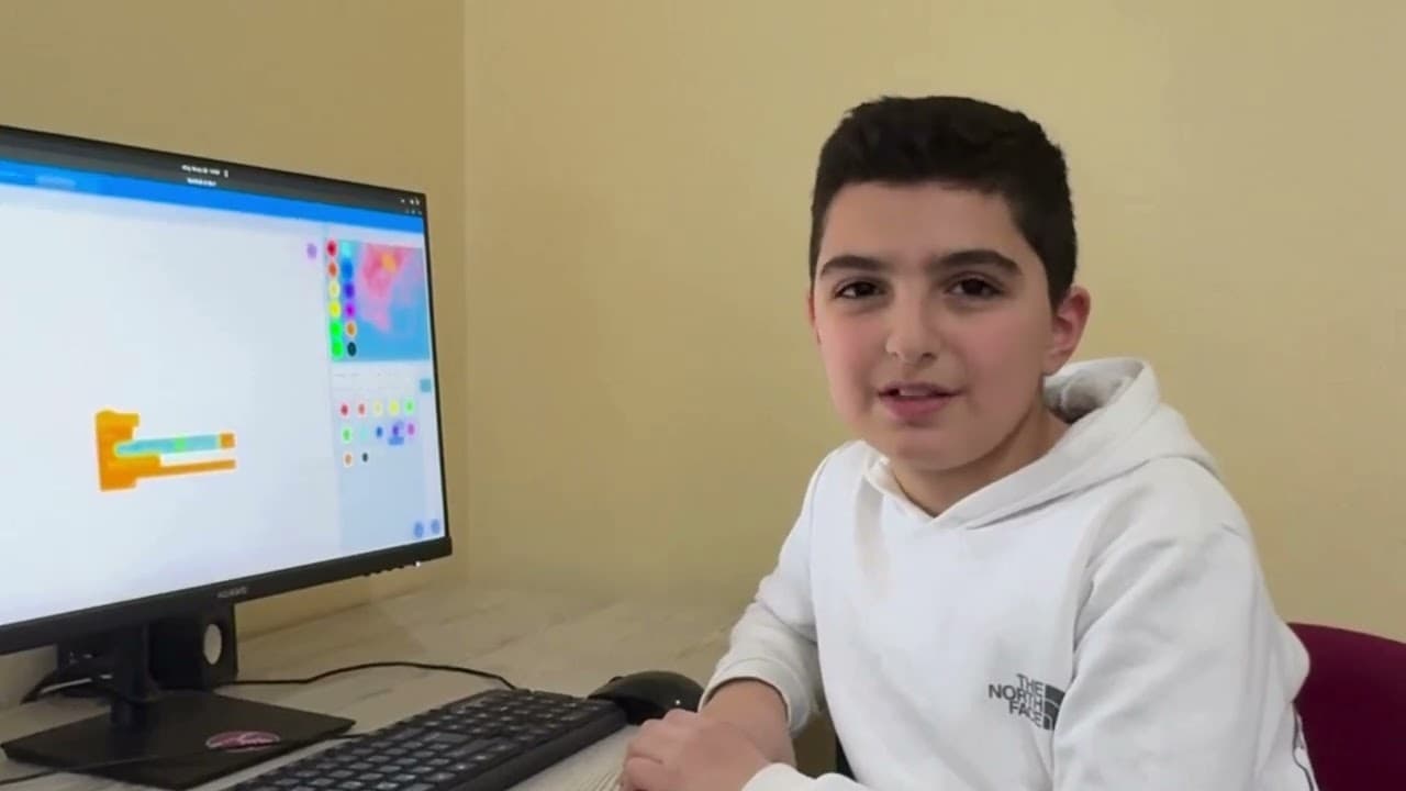 A participant speaking beside a computer in the film about the 2024 Bebras challenge.