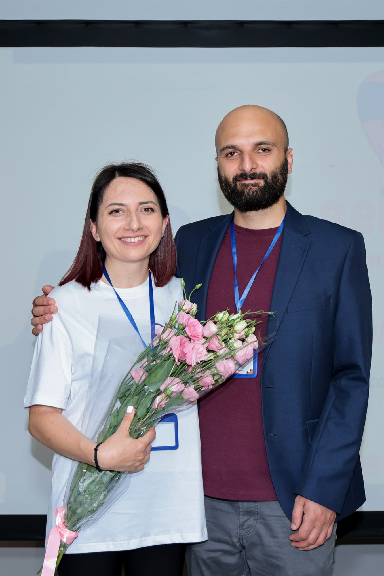 Gohar and David Khachatryan standing together at the Bebras award ceremony, Gohar holding a bouquet.