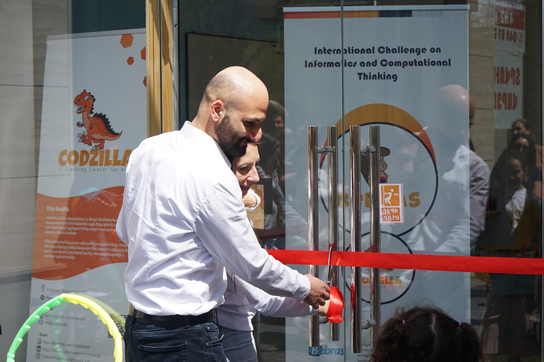The founders cut the ribbon at the opening of the Codzilla centre, under the Codzilla and Bebras banners.